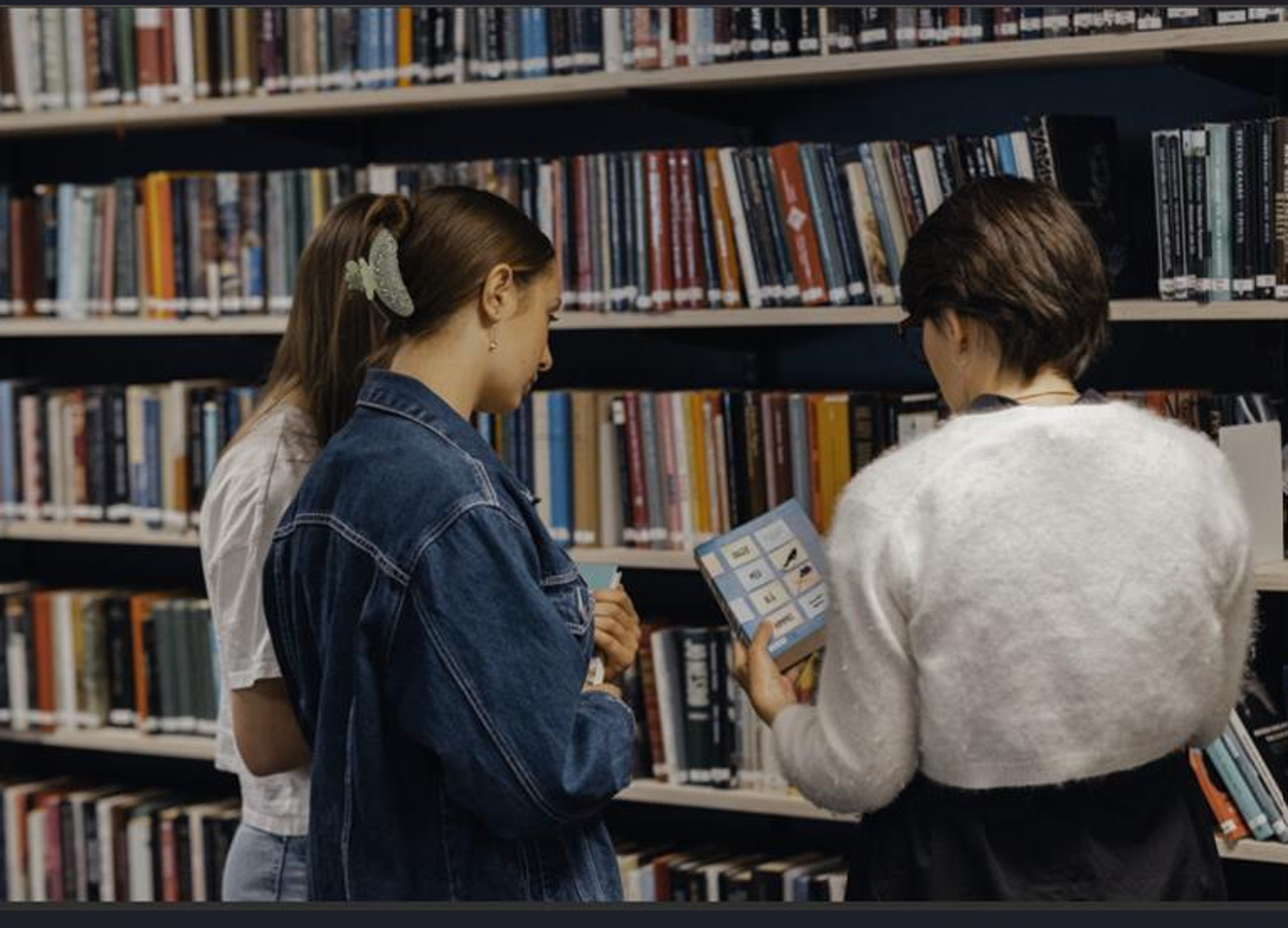 et par personr som ser på en bok på et bibliotek