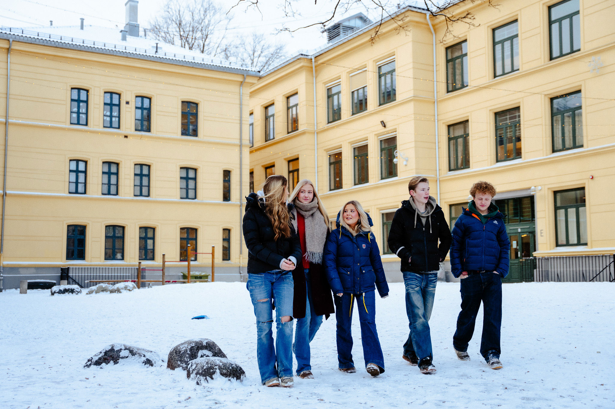 en gruppe mennesker som står i snøen foran en bygning