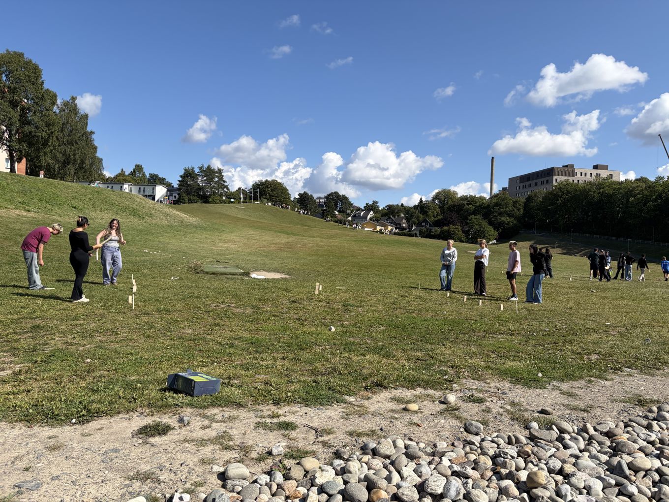 En gruppe mennesker på en gresskledd ås
